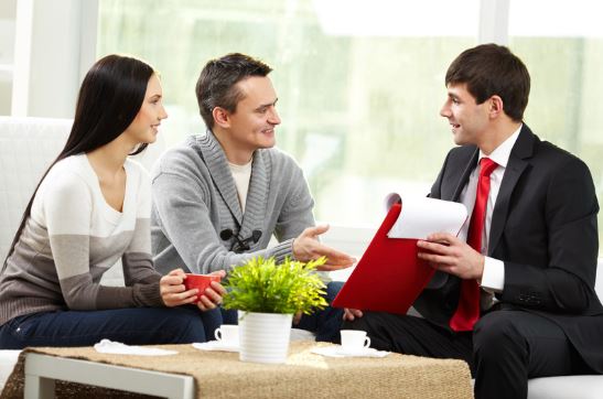 couple with mortgage loan agent holding red clipboard