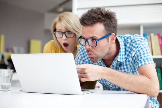 Surprised Couple Looking at Laptop Screen